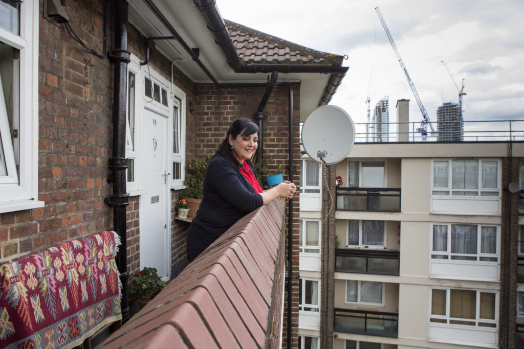 A woman stands outside her top-floor flat in Islington, London and looks out over the view. 